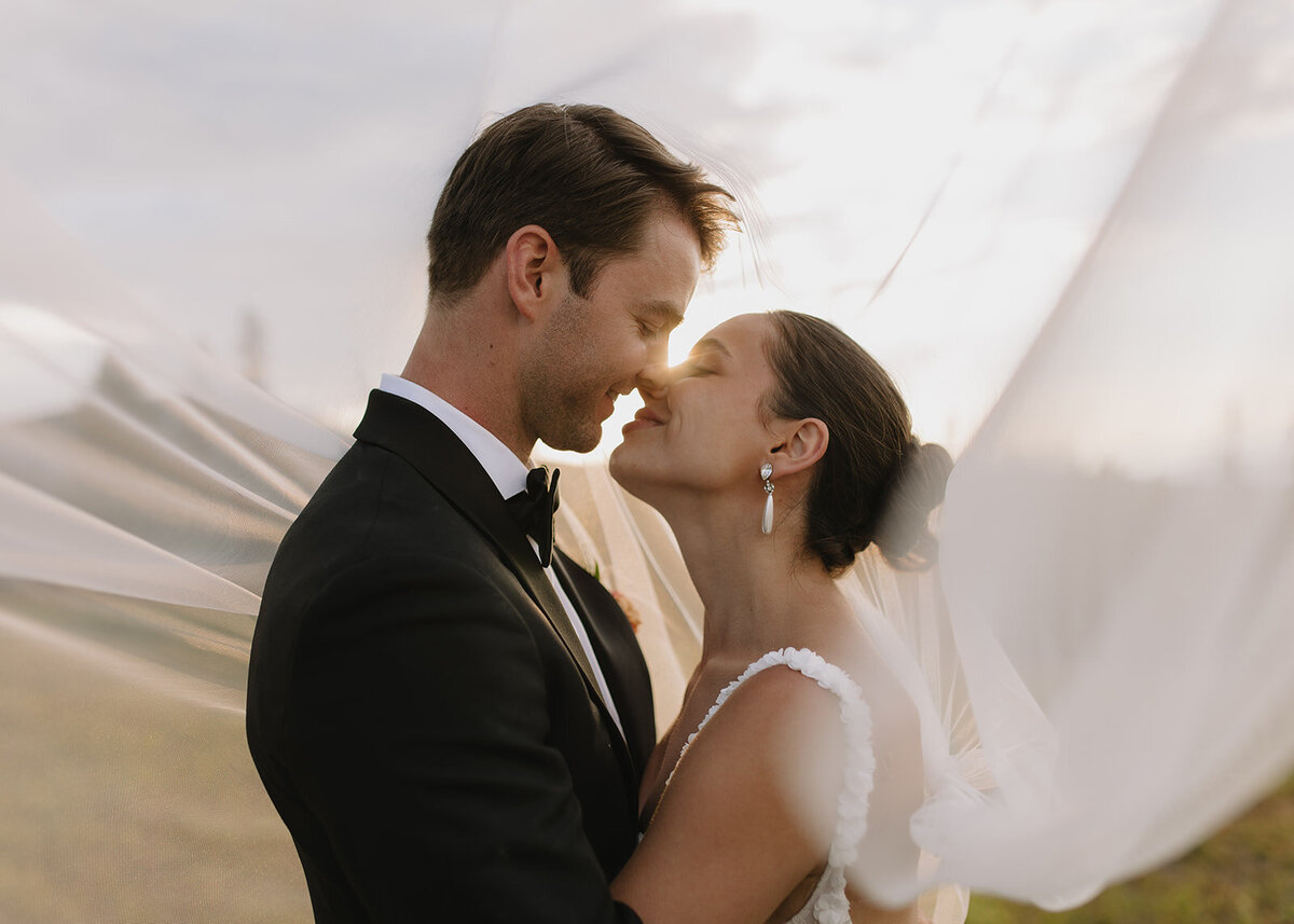 Married couple kissing under veil