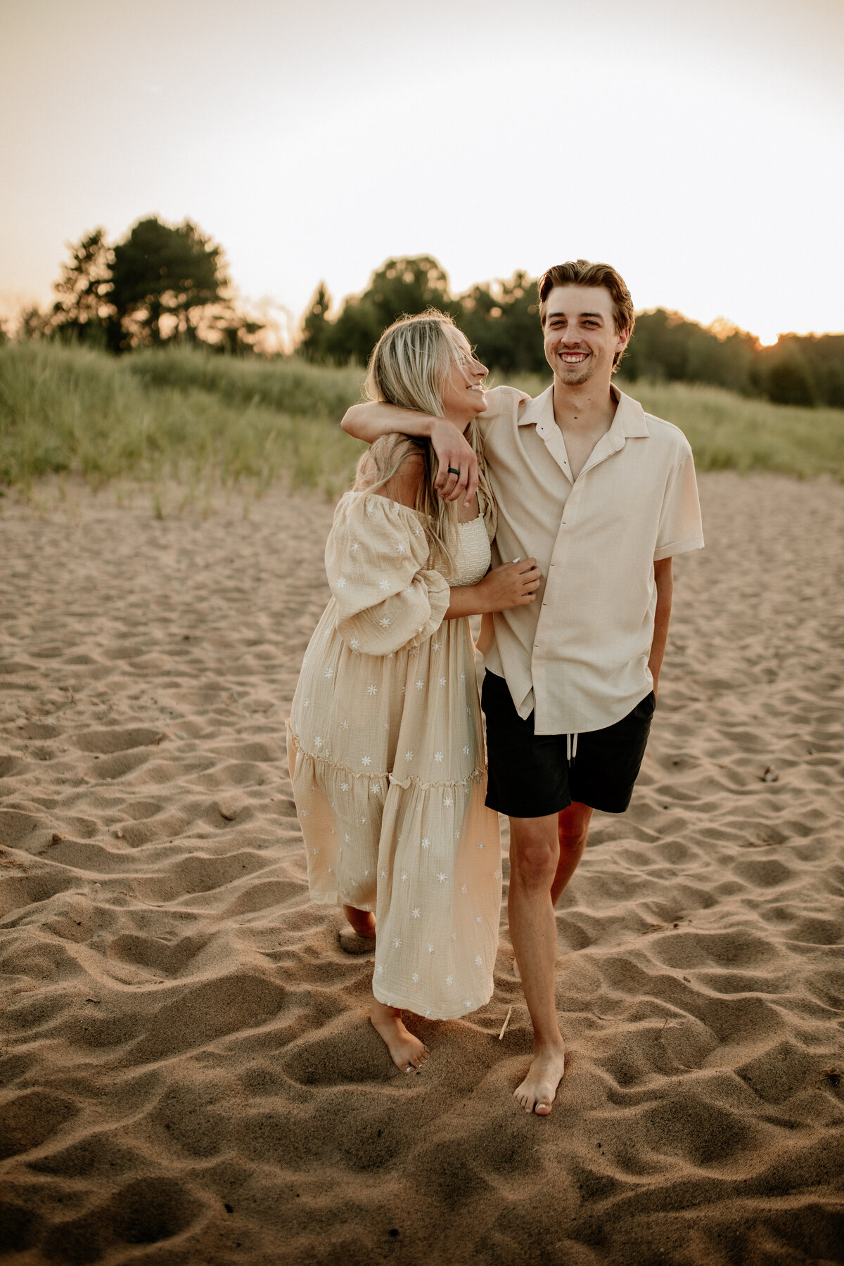 Wisconsin couple walks barefoot through the sand along the lake.