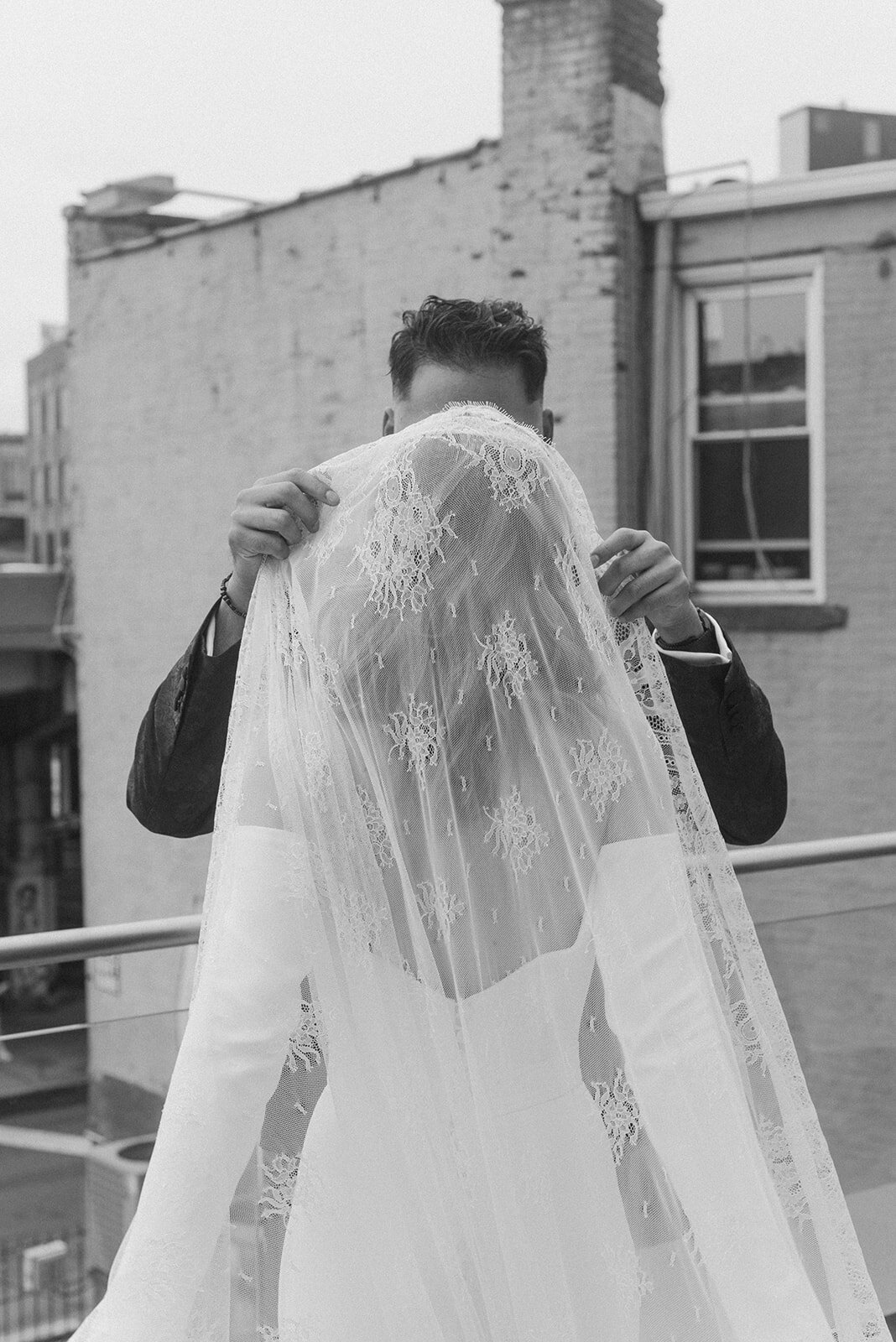 groom lifting bride's veil on a rooftop in brooklyn, ny 