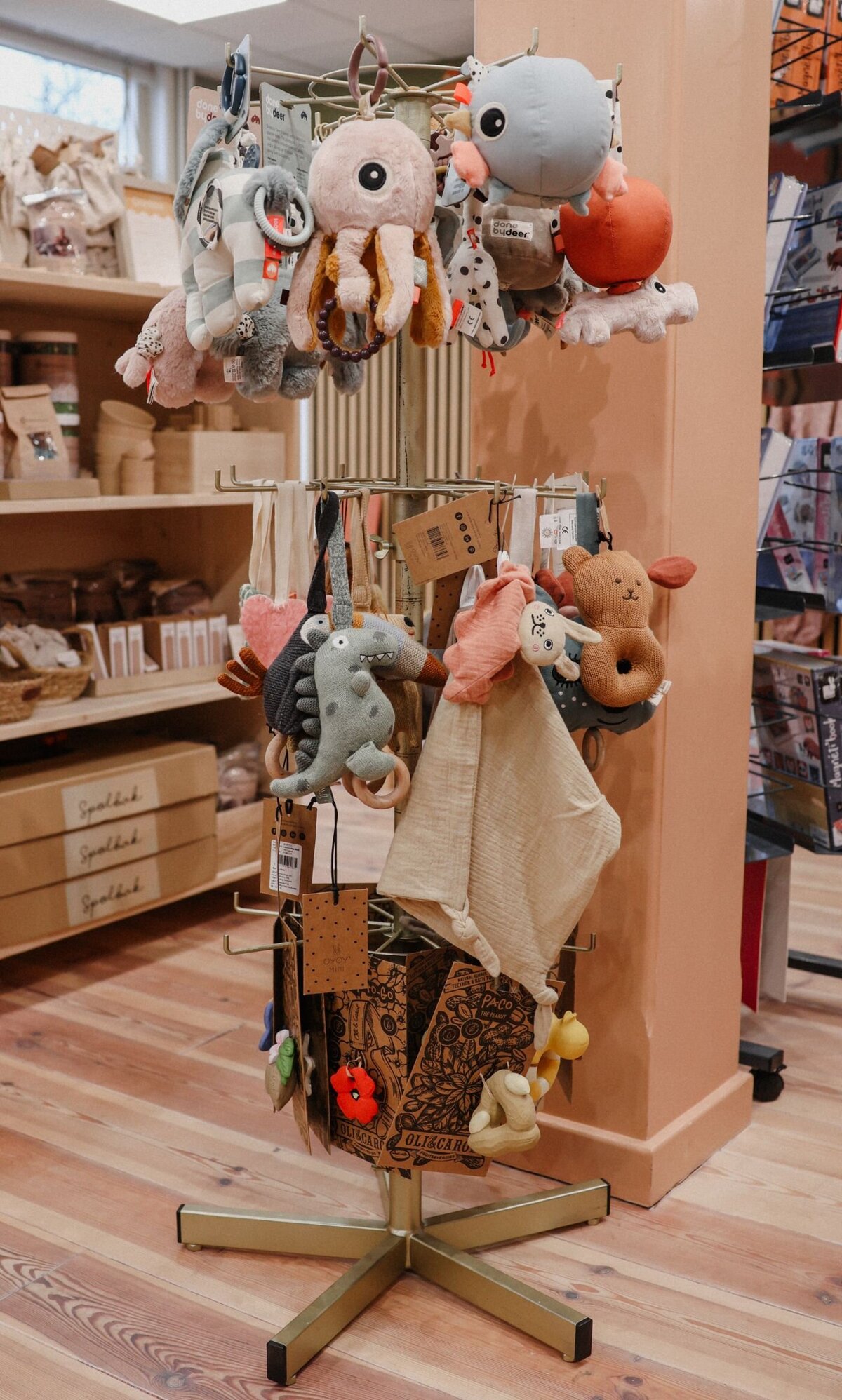 Draaibaar rek met knuffels en stoffen speelgoed in een winkel met houten vloer.