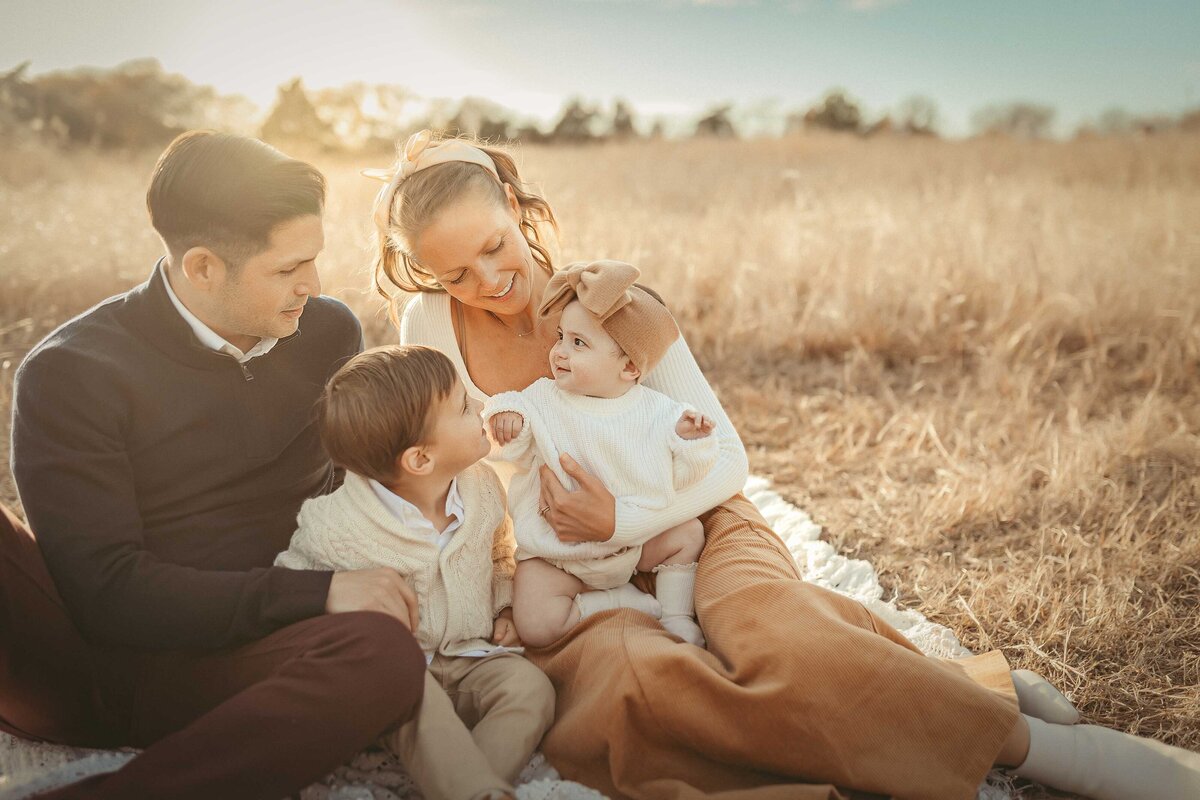 A man  with his wife and children smiling at their family photography session in Plano, TX