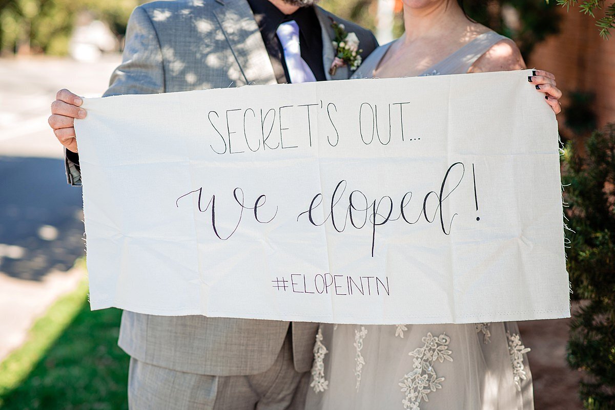 Secret's Out! WE ELOPED! #elopeintennessee fabric sign being held up by the bride and groom.