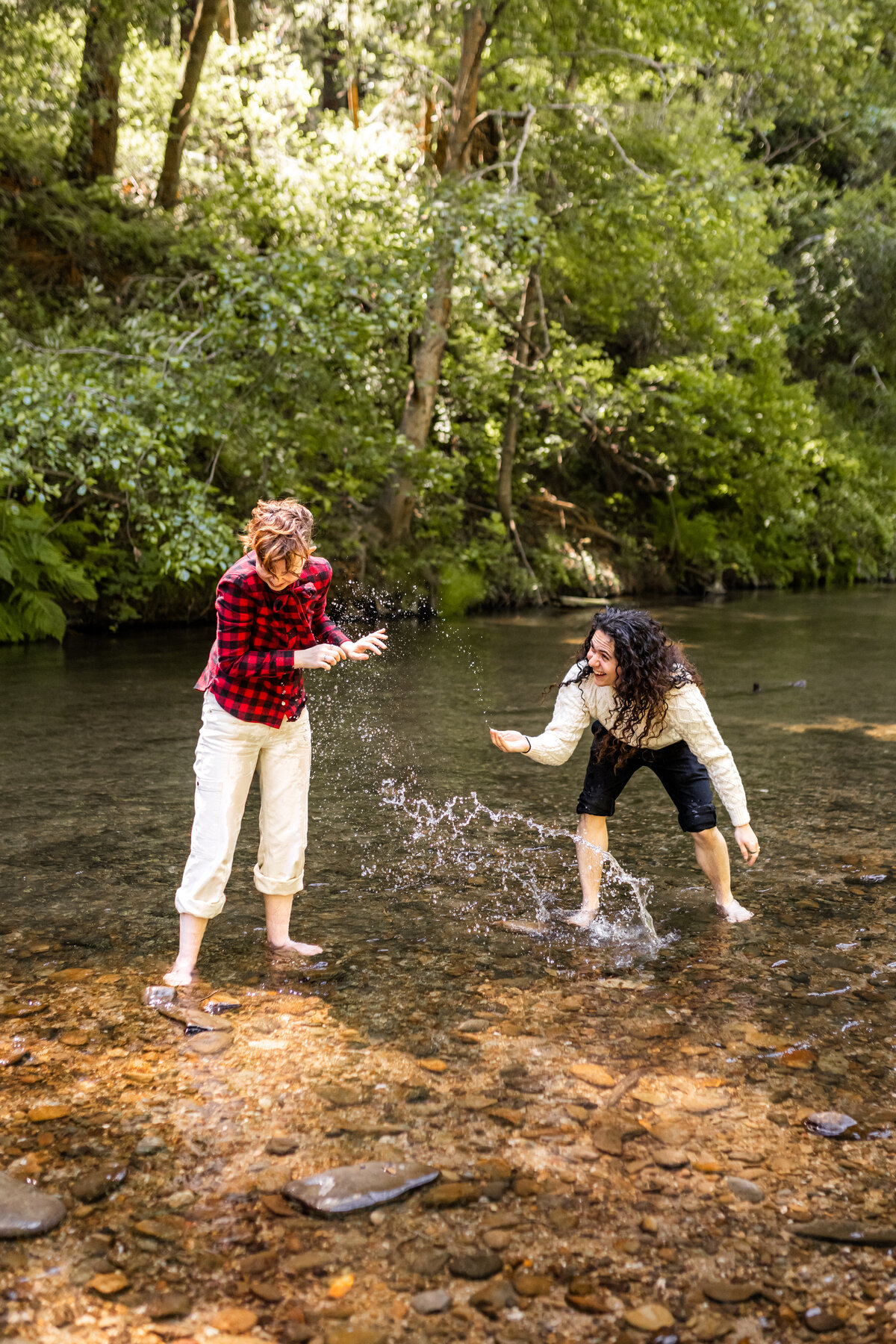 queer couple splashes in river for their casual engagement photos