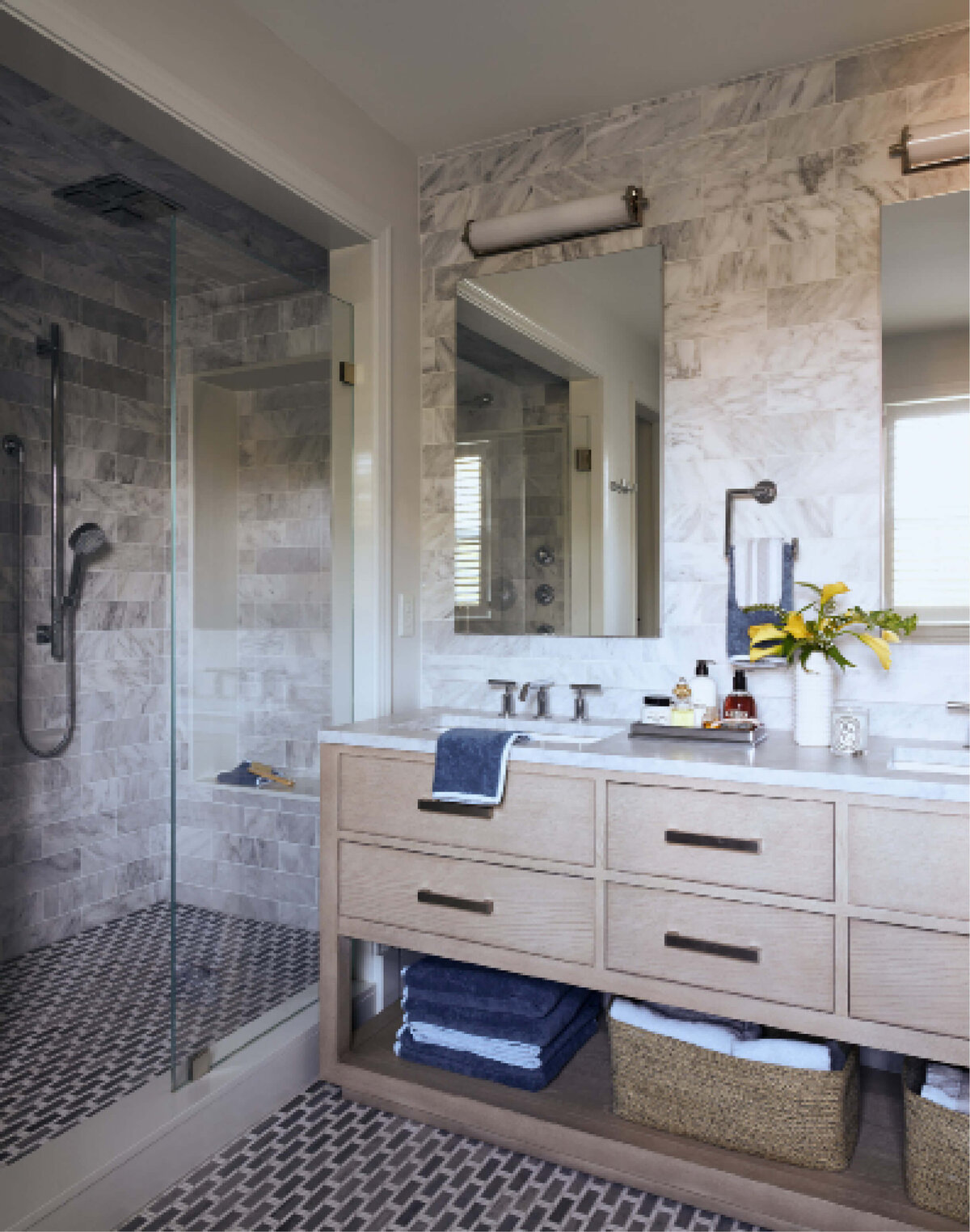 Interior designers in Hingham create a primary bath in a historic home with a natural wood vanity, marble backsplash, and stone mosaic flooring for a timeless look.