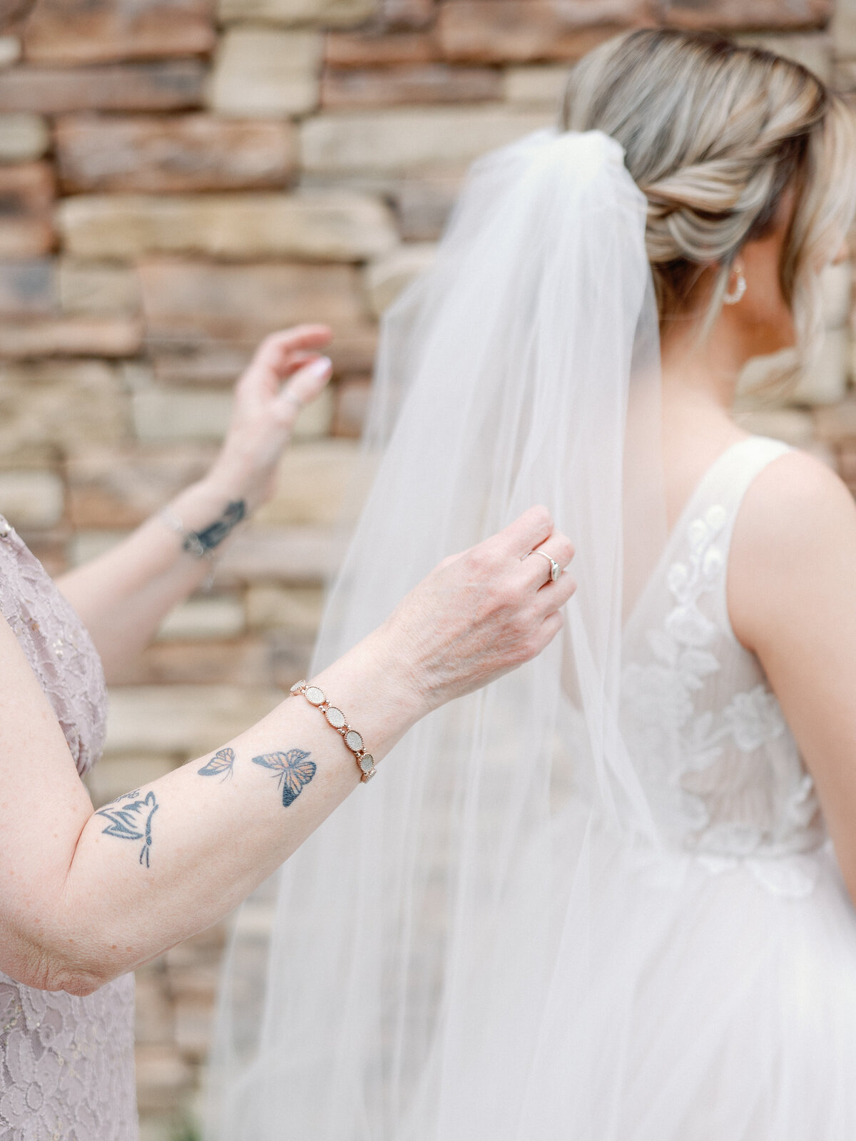 A mom helps her daughter place her wedding veil in her updo before her ceremony