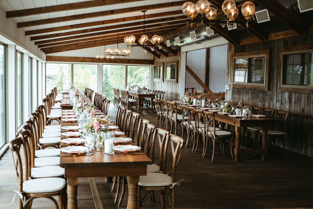 long feasting tables and cross back chairs set up in the reception dining area at Willowbrook wedding venue