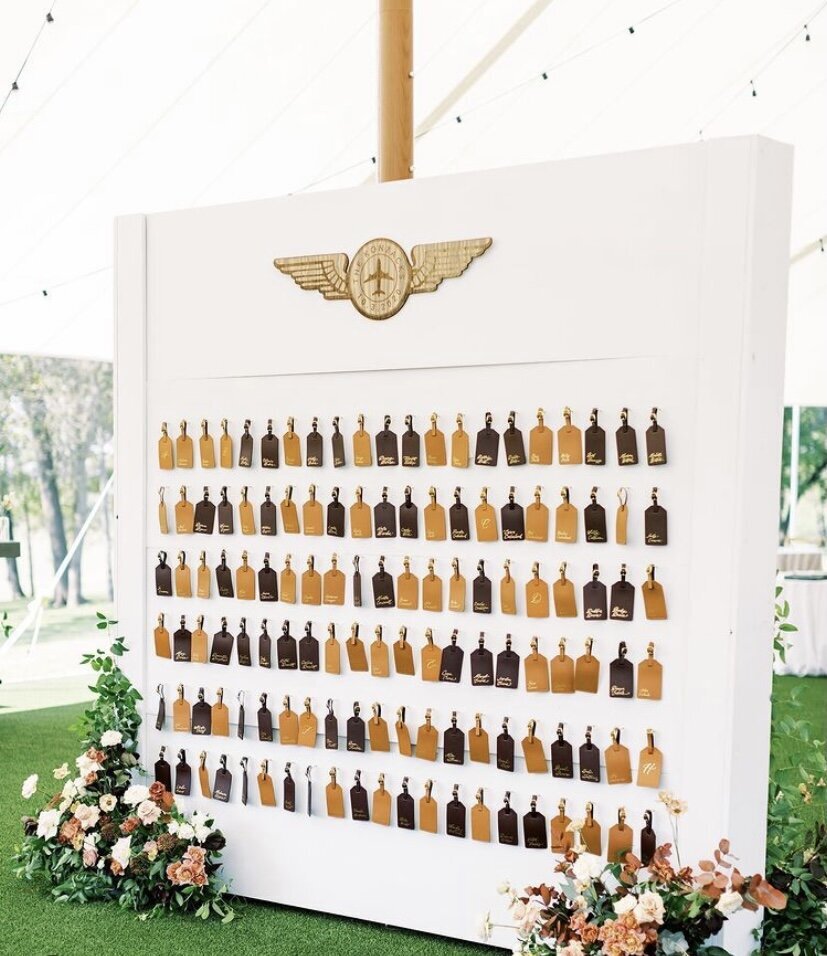 Wedding reception white seating chart decorated with brown name tags and florals