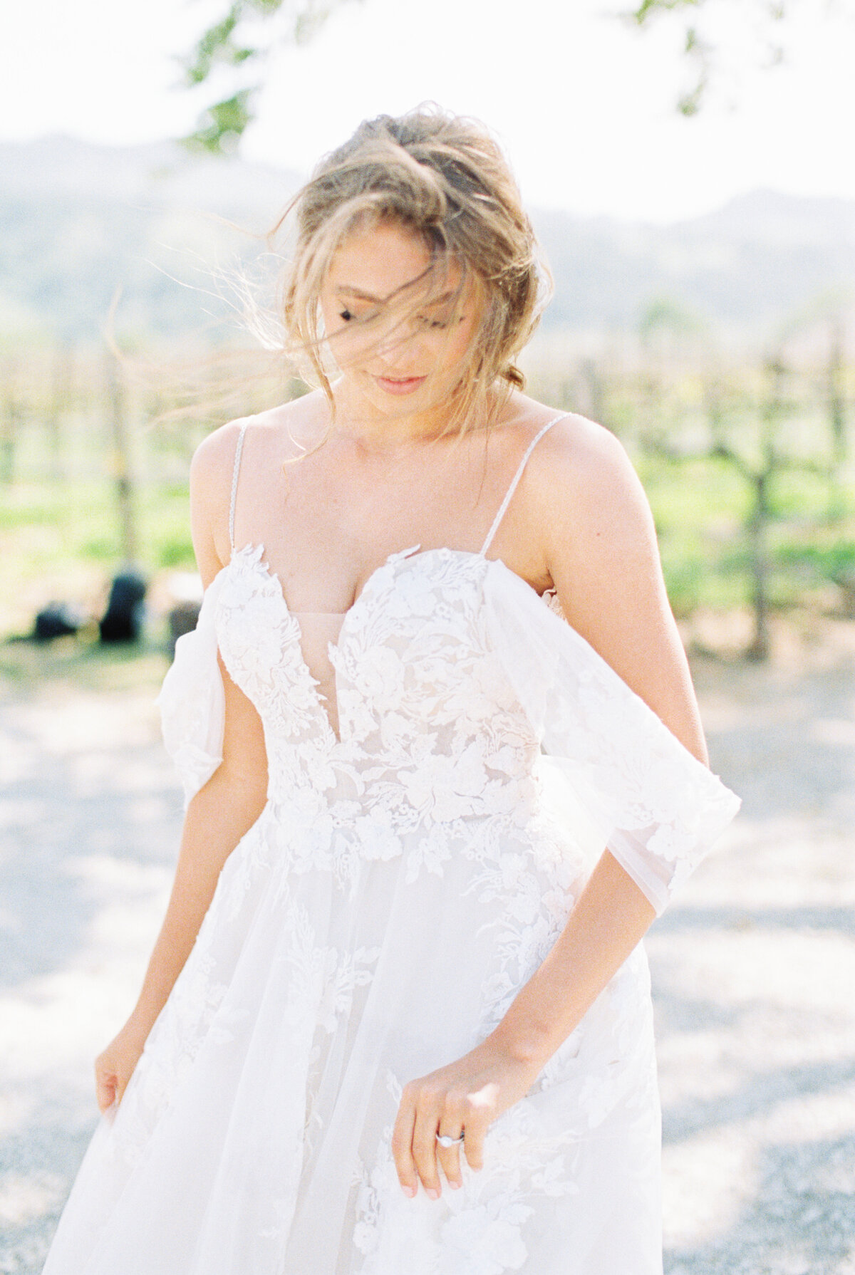 bride fixing her dress as the wind blows her hair