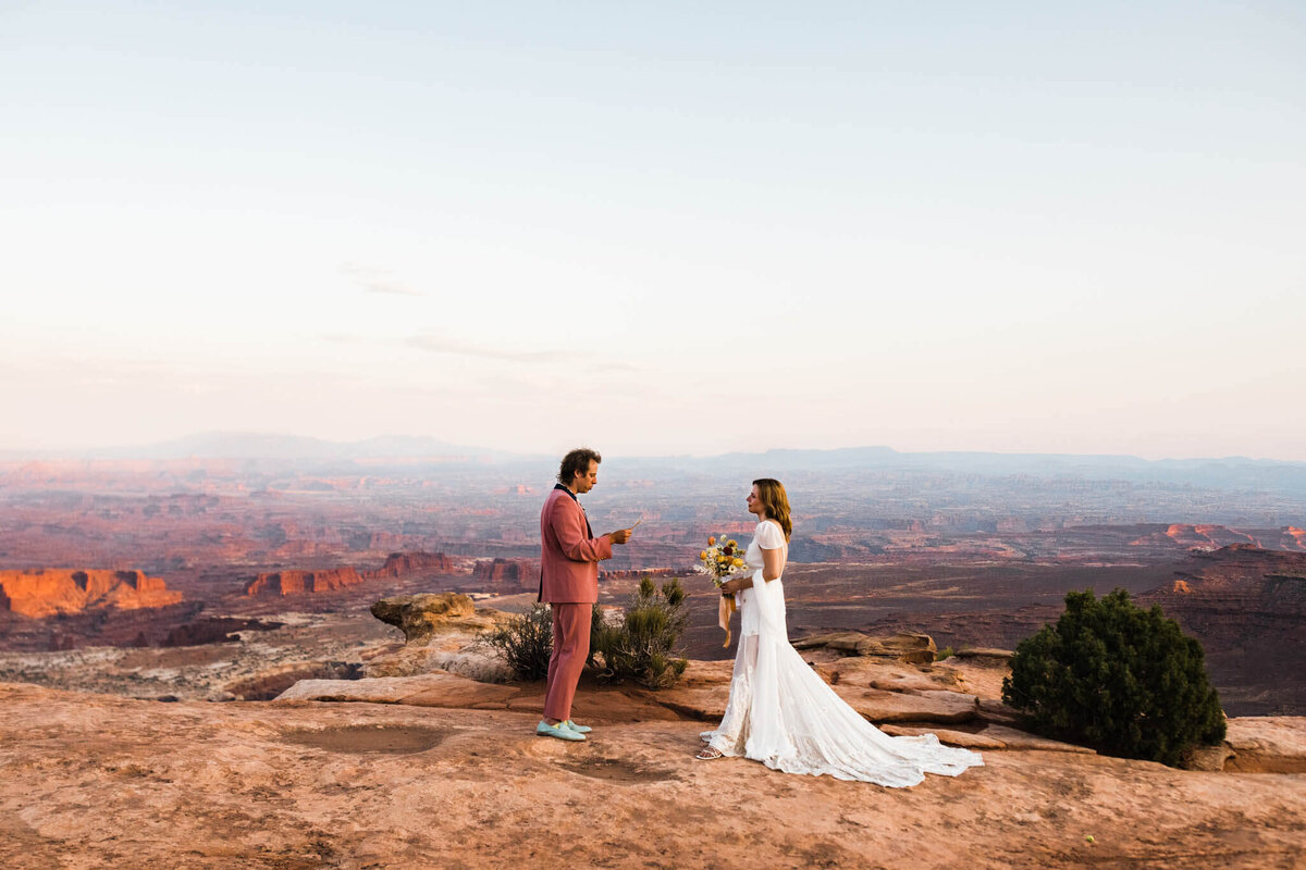 the groom looks back at his smiling bride as he leads her through the smooth slot canyon halls