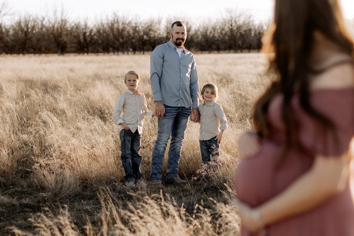 dad with two sons a short distance behind pregnant mom