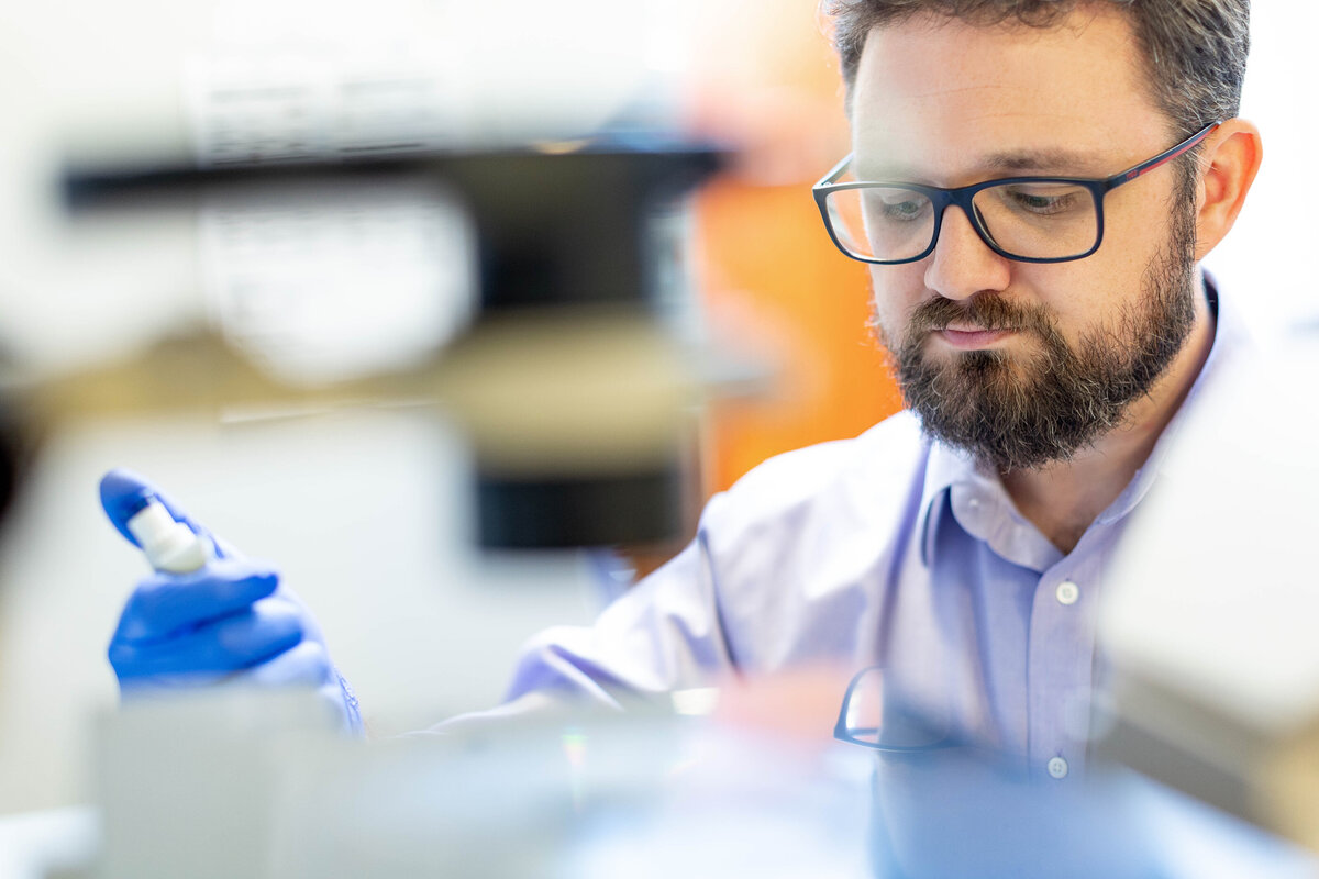 Man with glasses pipetting in lab
