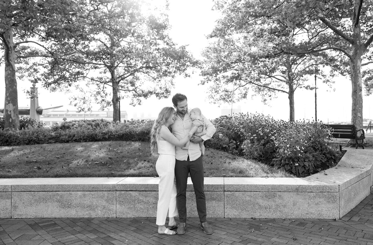 Mother and Father hold child and smile during outdoor session in boston.