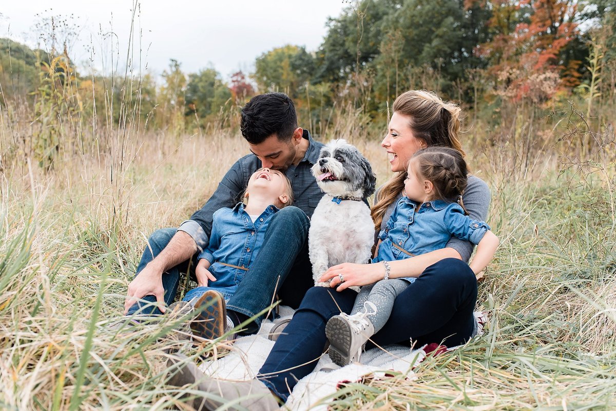 Family with dog laughing in field