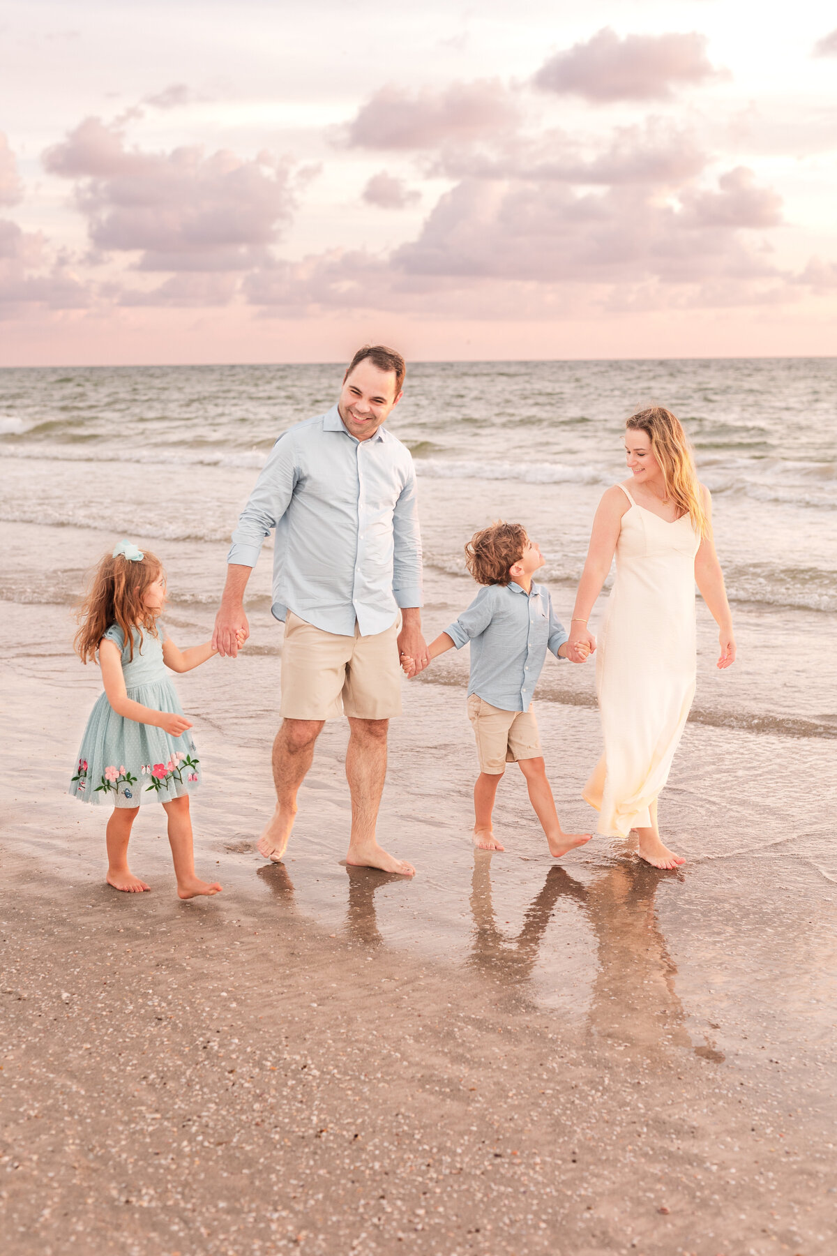 Parents and kids walking on Clearwater Beach with the setting sun behind them.