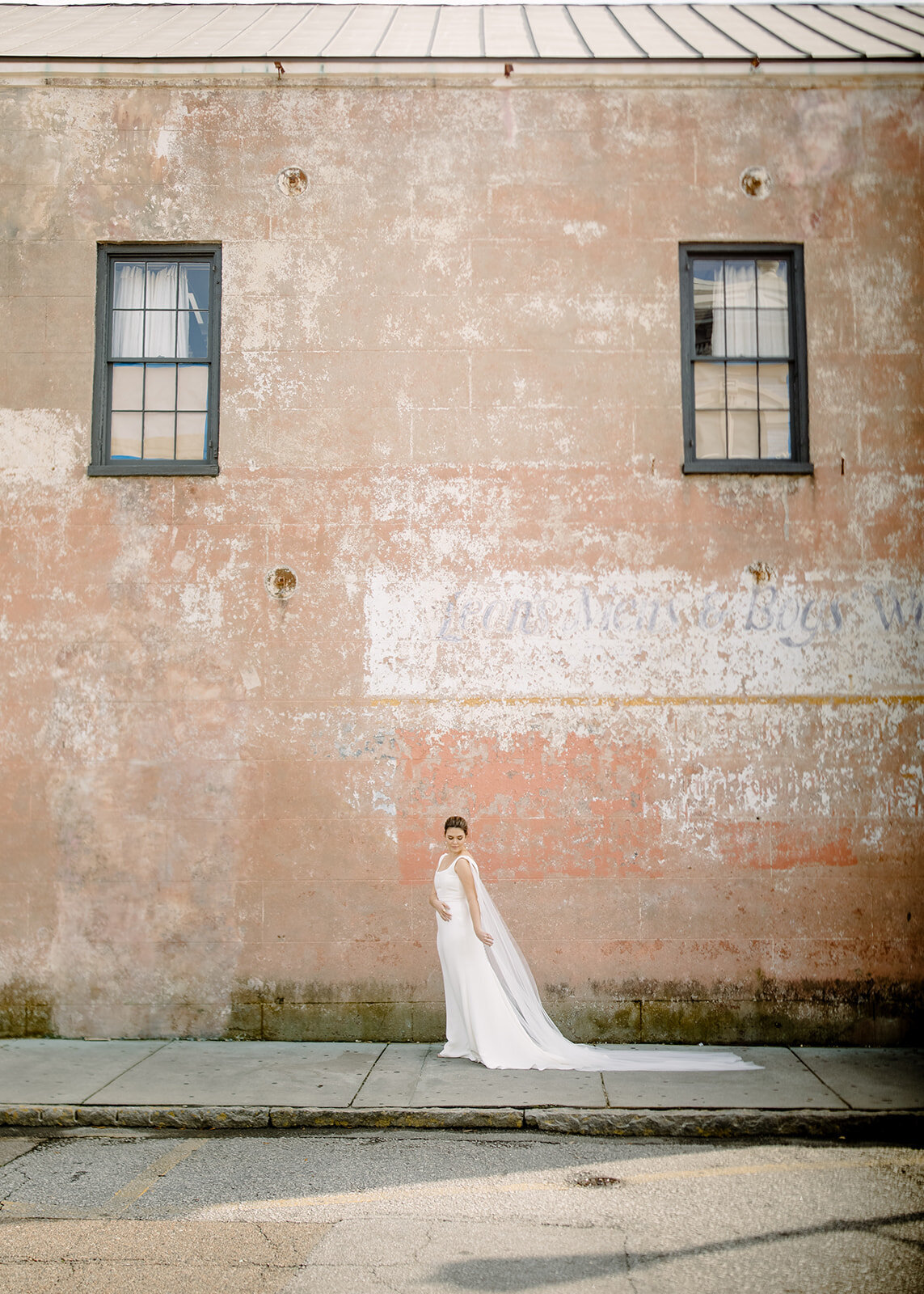Bride posing in front of an outdoor building wall in Charleston
