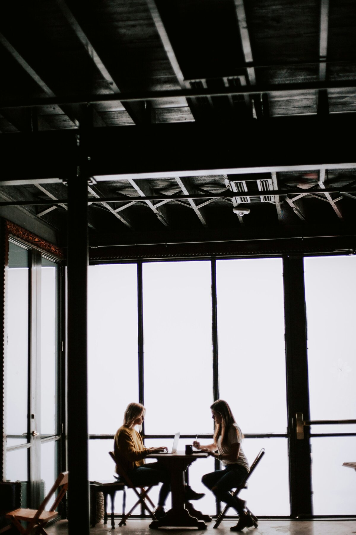 2 women in front of a window working on a laptop 