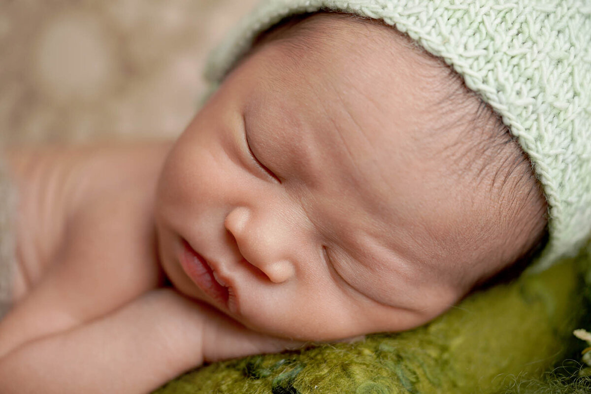 Closeup of newborn sleeping on green blanket