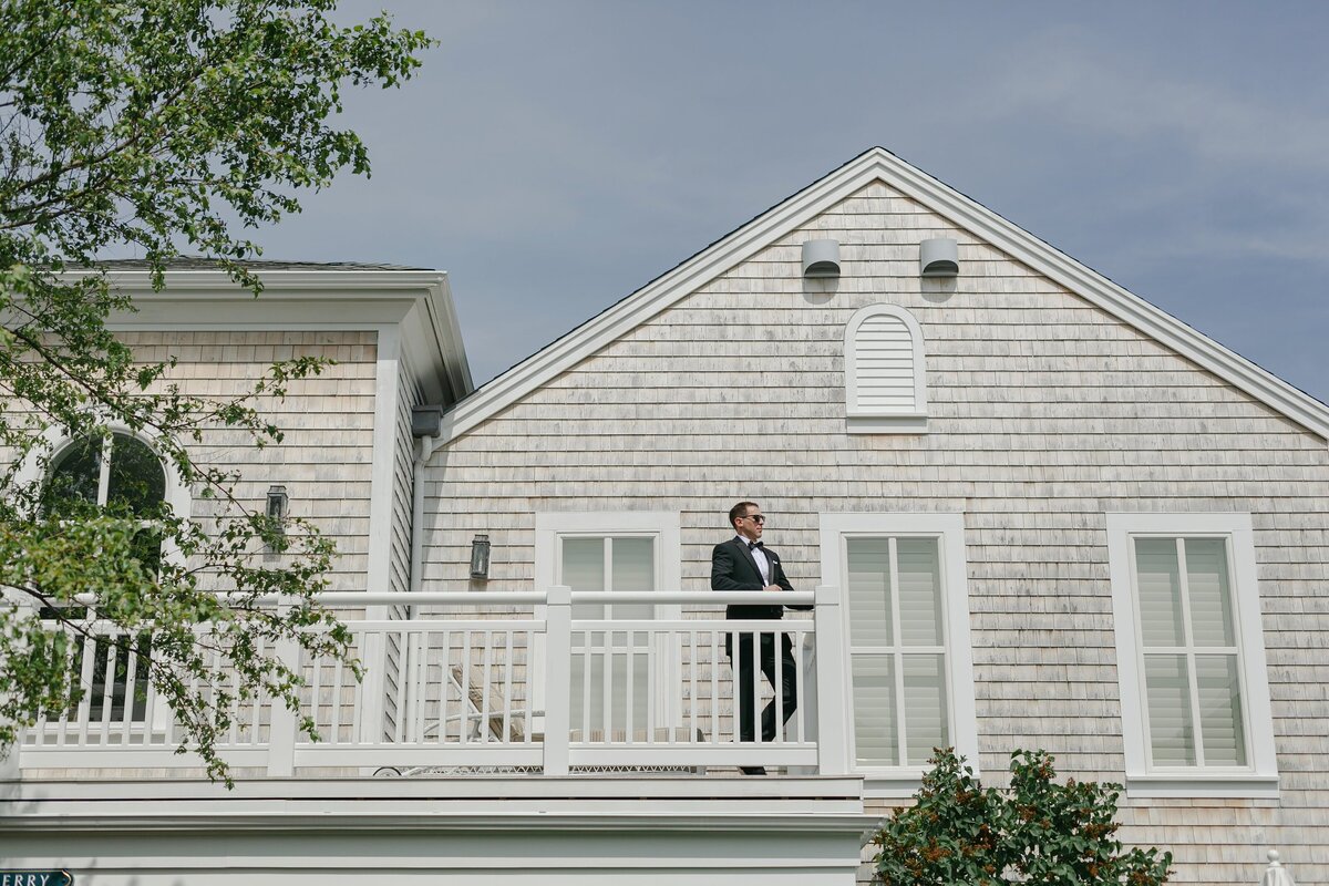 Groom stands on balcony as he gets ready for wedding at Wequassett.