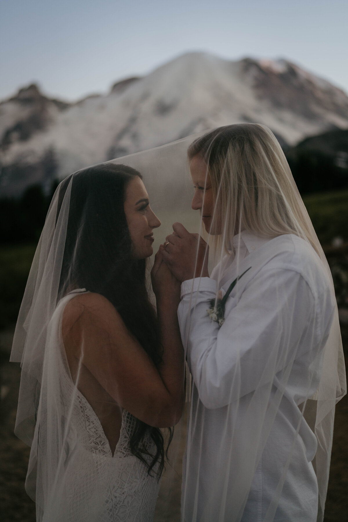Bride and bride cuddling up close under veil  during Mt Rainier elopement