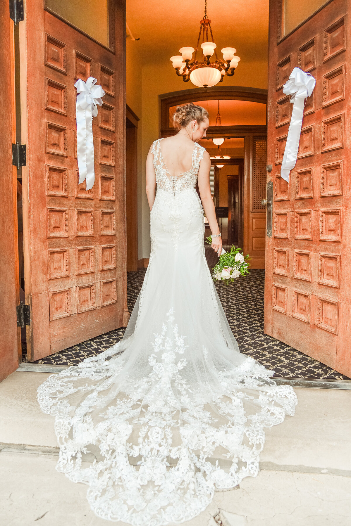 Bride showing off the back of her dress with flowers by her side at the Cardome Center