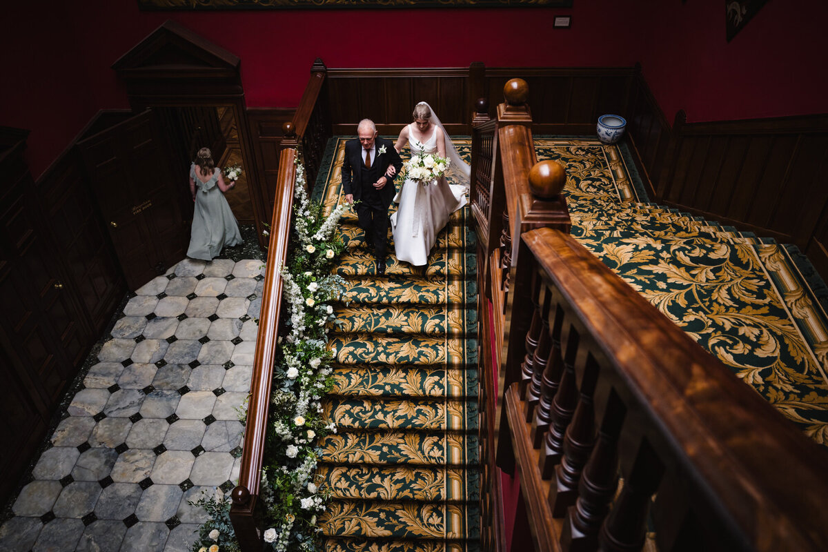 Bride and groom walking down stairs at Stapleford park hotel