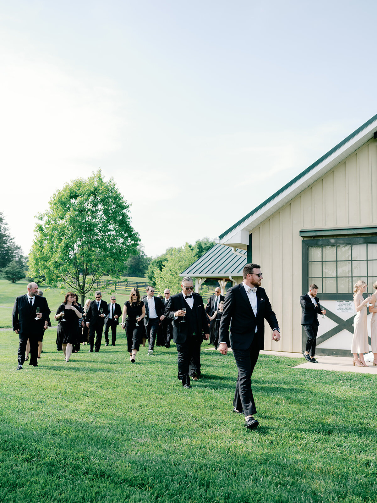 Guests wearing all black walk towards wedding ceremony space