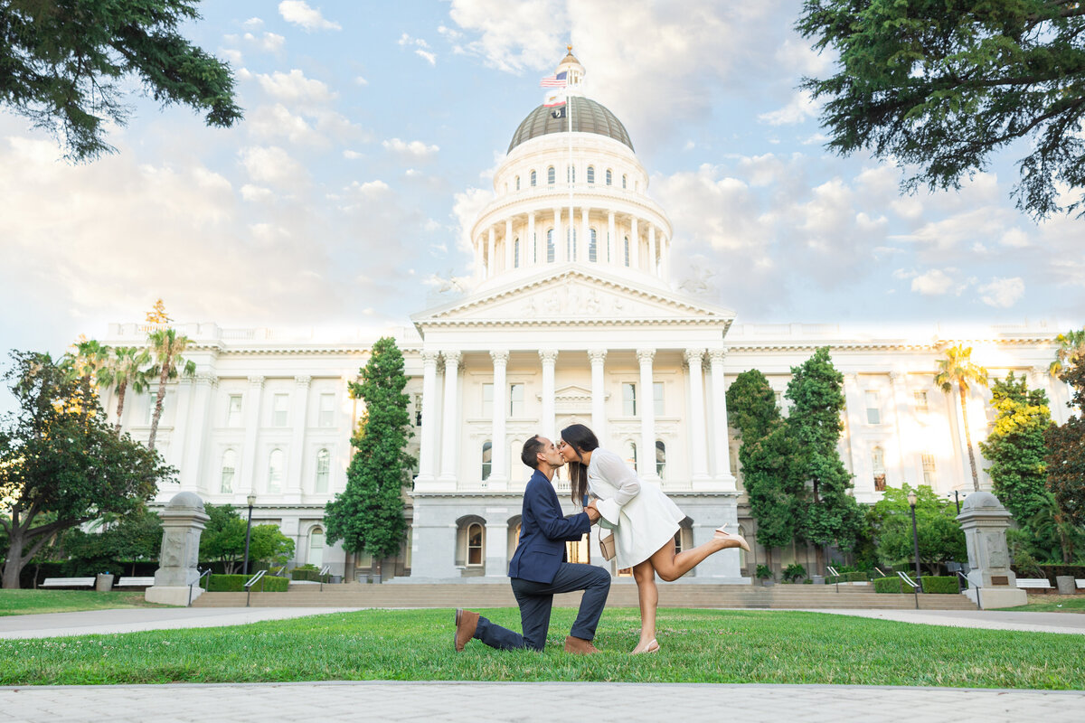 Man proposes to woman in front of Sacramento state capitol building. She kisses him after receiving the ring. Photo by Philippe Studio Pro.