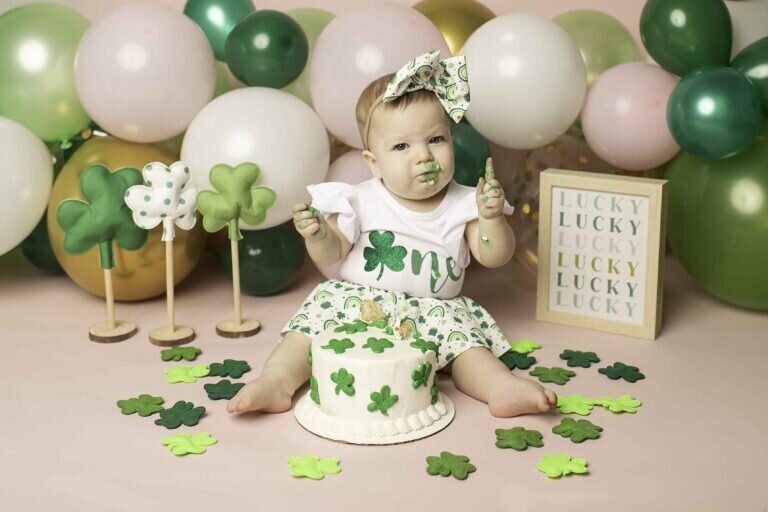 One-year-old birthday boy smiling joyfully in front of a colorful backdrop during his first birthday photoshoot