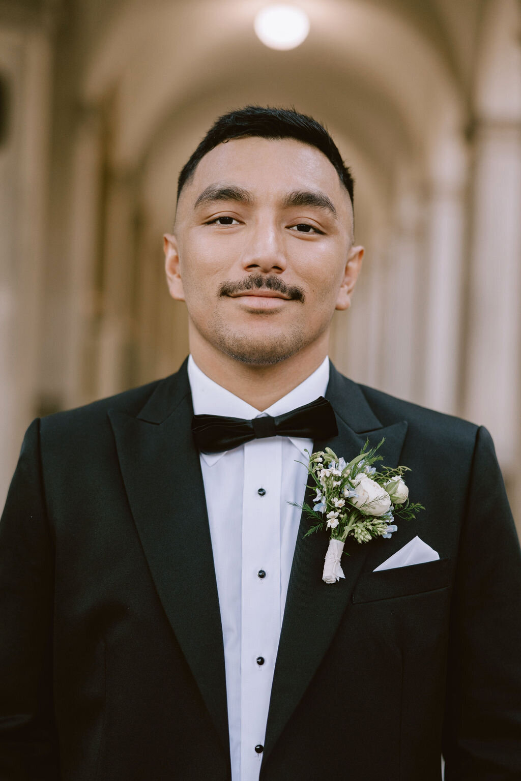 groom portrait with arches behind him