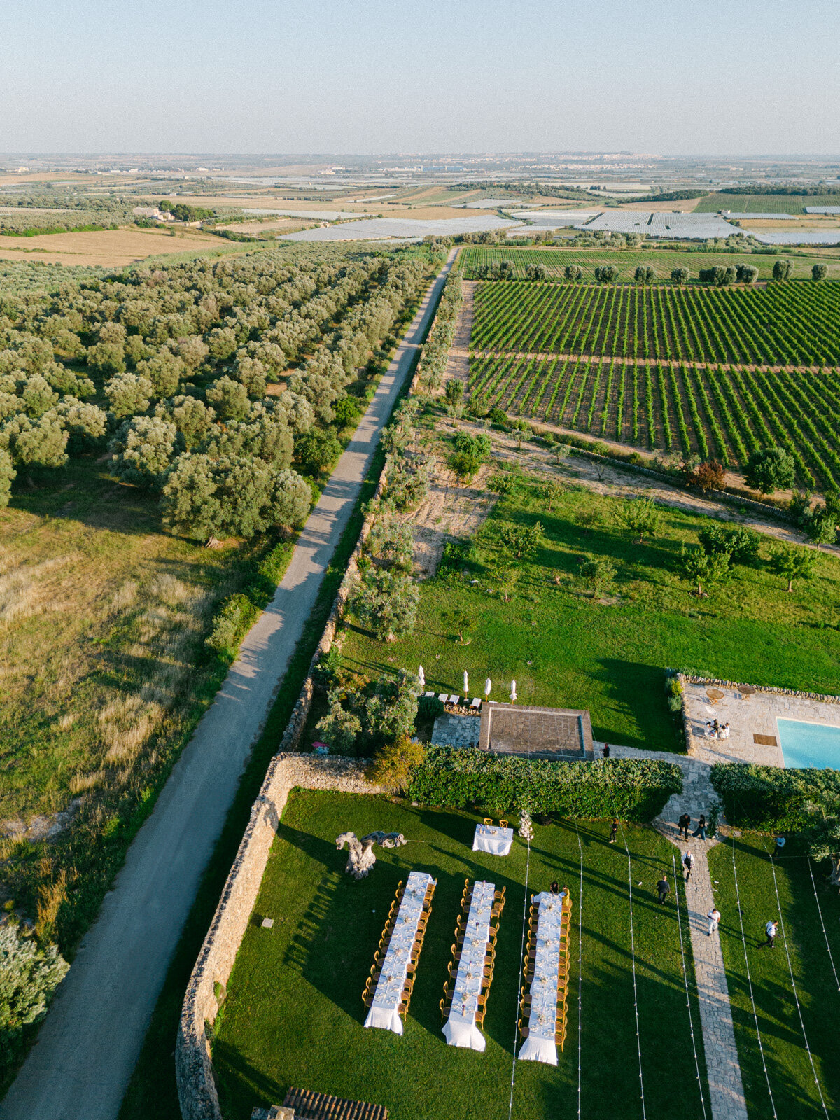 Luxury wedding venue in Italy surrounded by vineyards and olive groves – aerial view of outdoor reception setup.