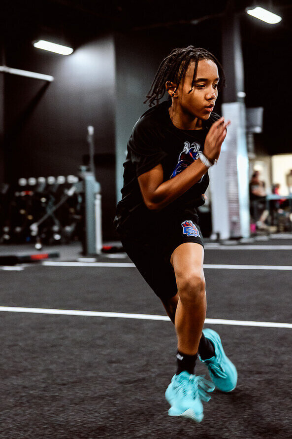 Young boy football player trains on an indoor turf.