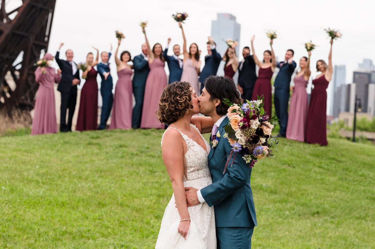 Bride and groom kiss in front of their wedding party at Tom Ping Memorial Park in Chicago.