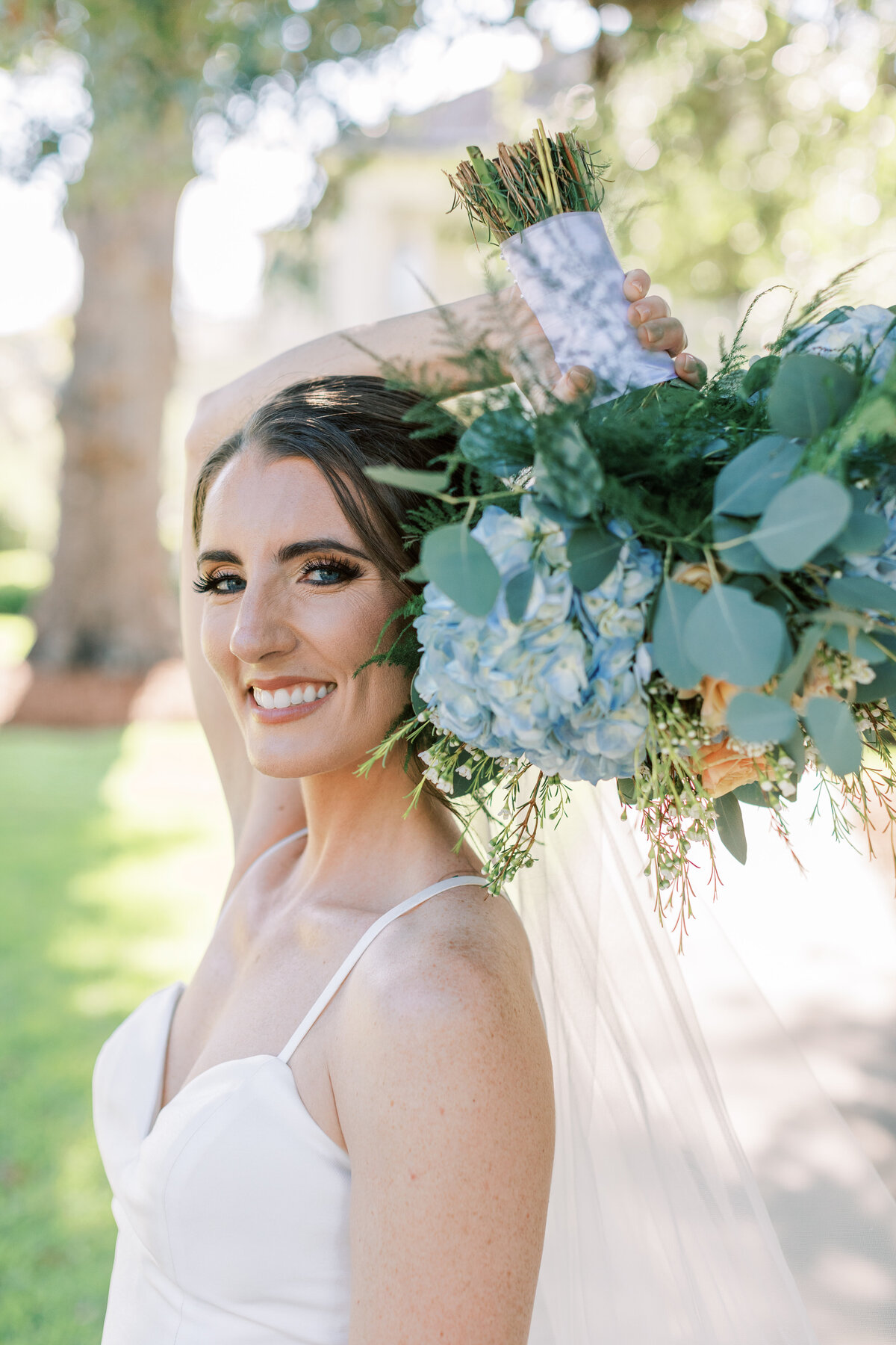 A bride holds her bouquet above her head.