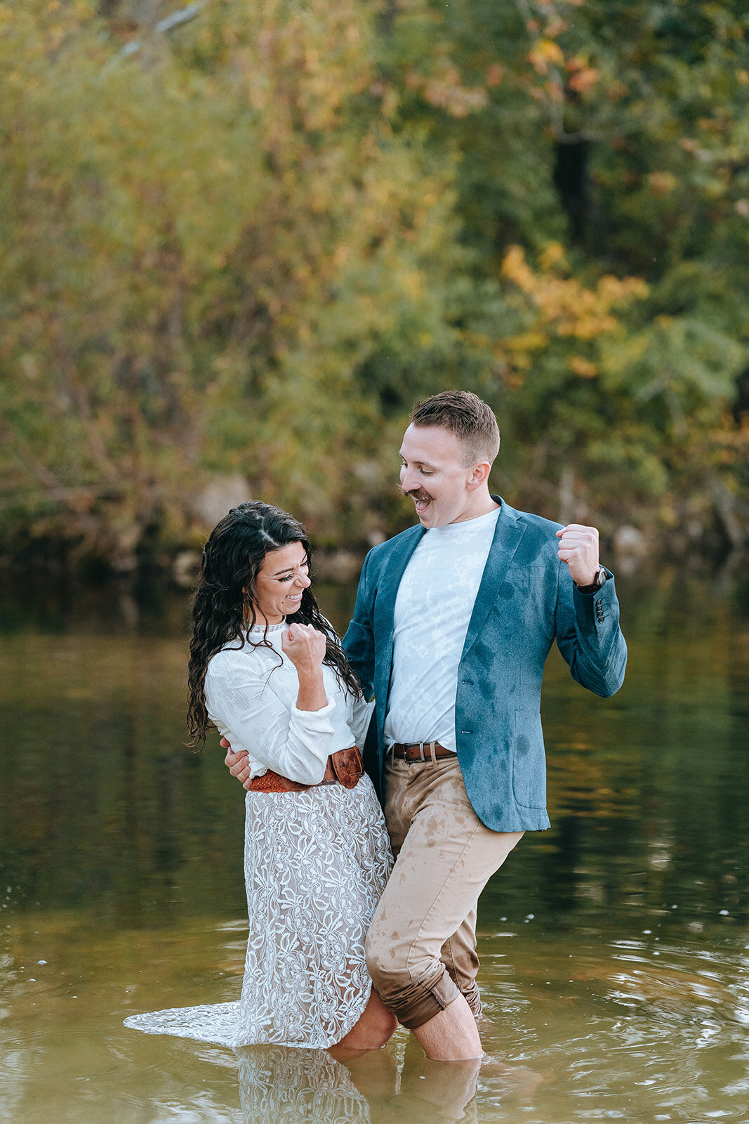 engaged couple celebrating and standing in lake