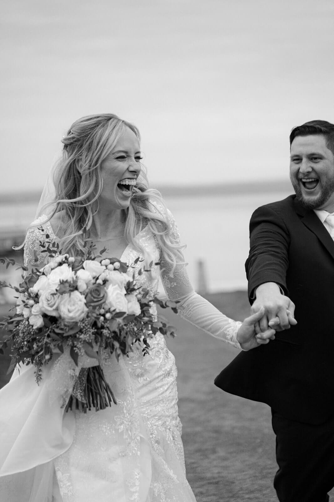 Bride laughing with groom holding her hand and laughing too