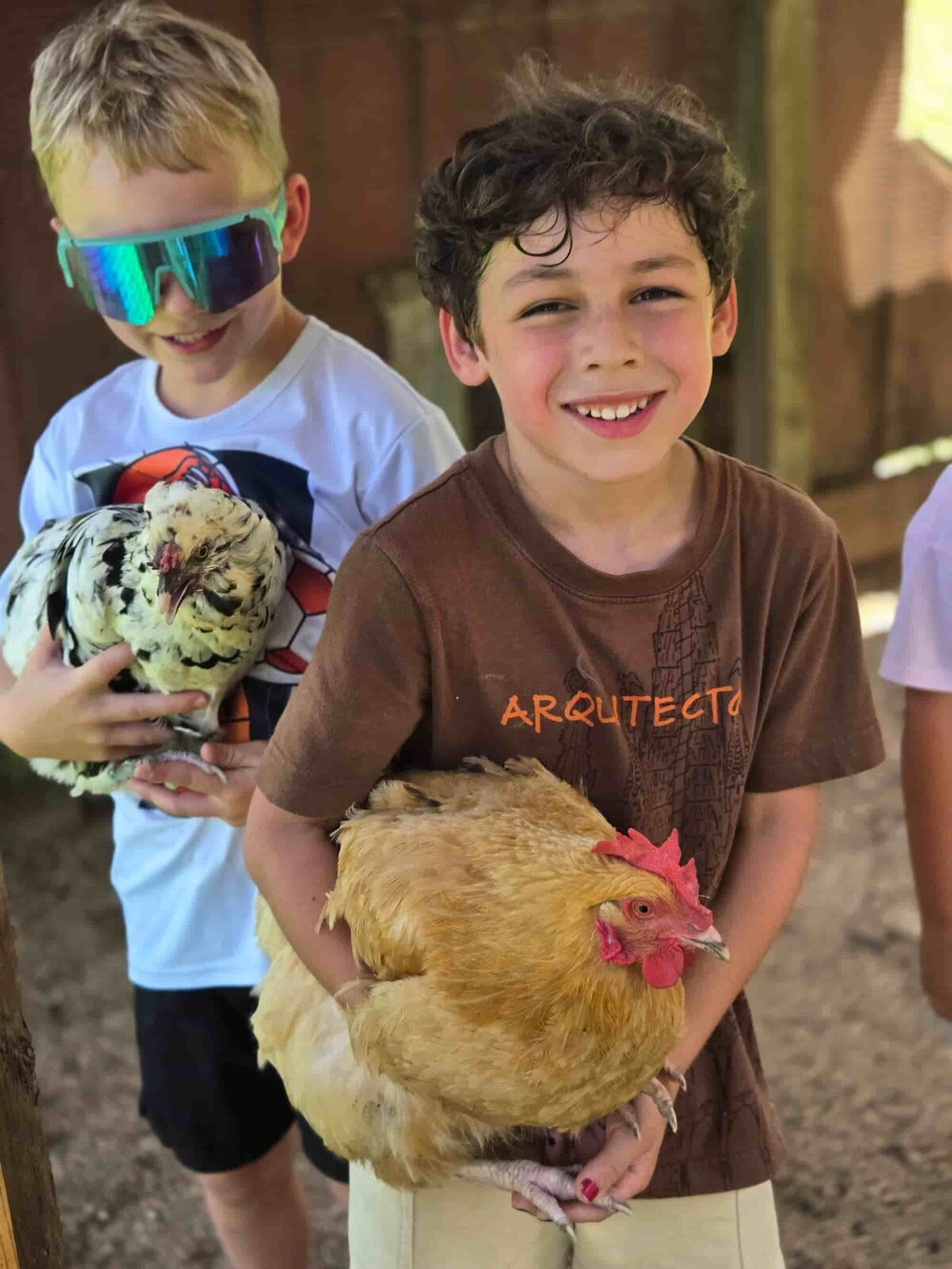 Two smiling ROOTS students holding chickens