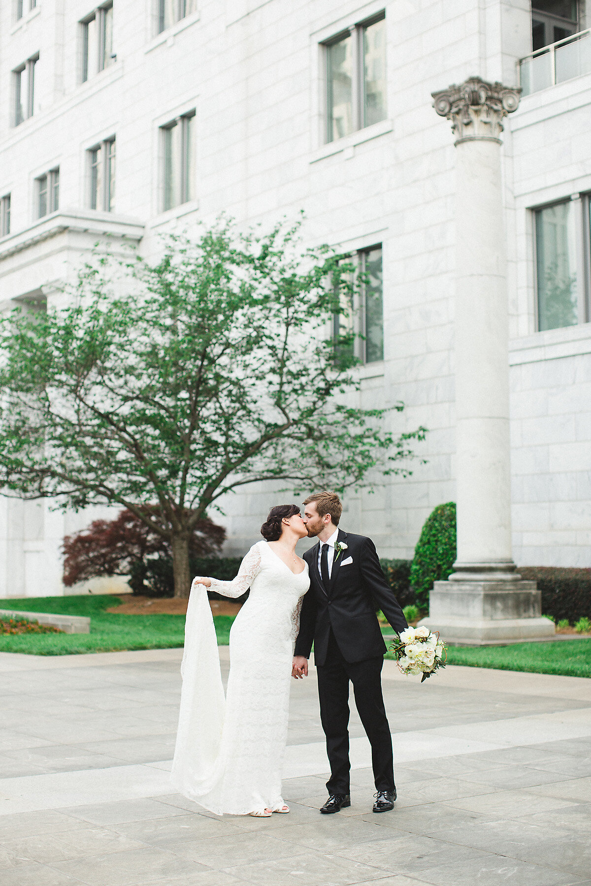 Bride and groom kissing in front of courthouse.