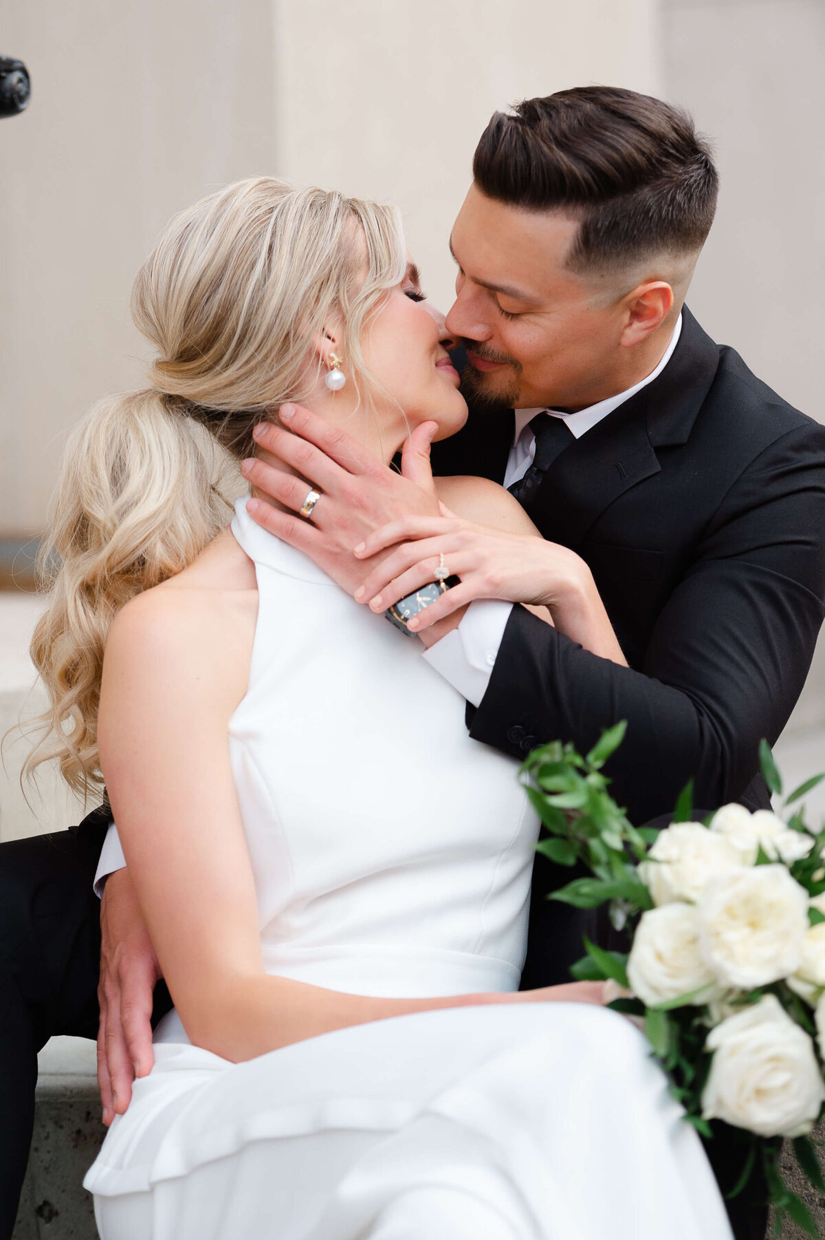 a bide and groom sitting on the stairs outside the Chateau Laurier hotel kissing taken by Ottawa wedding photographer JEMMAN Photography