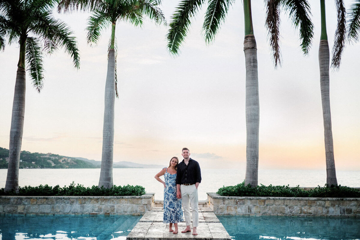 The engaged couple is standing on a concrete area in the middle of a swimming pool in Round Hill Hotel and Villas, Jamaica.
