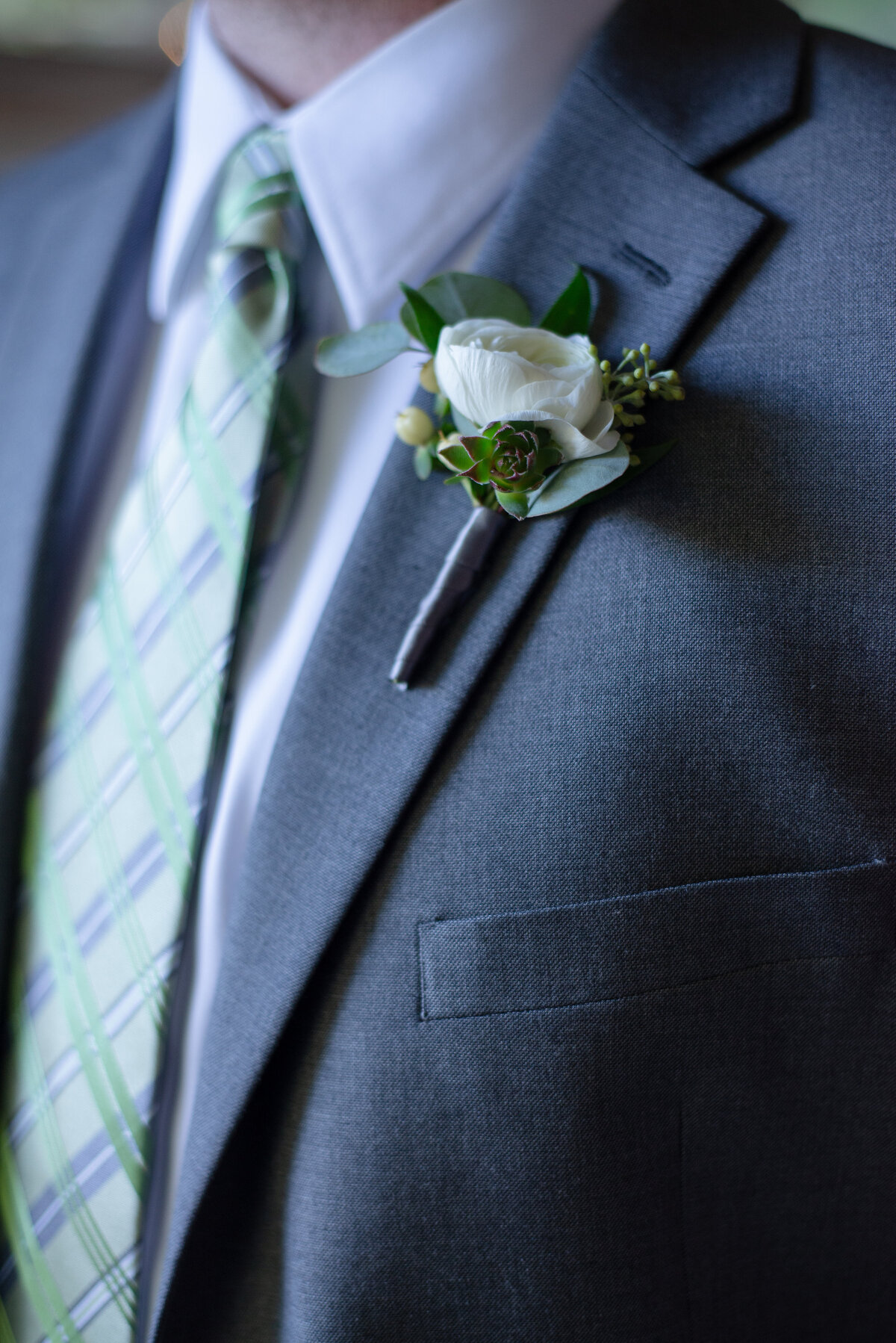 Wedding portrait of grooms details suit tie and boutonniere