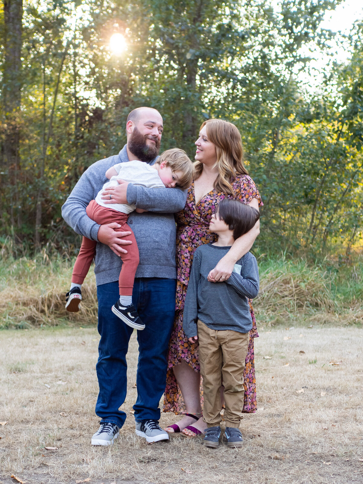 two parents smile at each other with their two kids at Wallace Swamp Creek Park, in Kenmore, Washington.