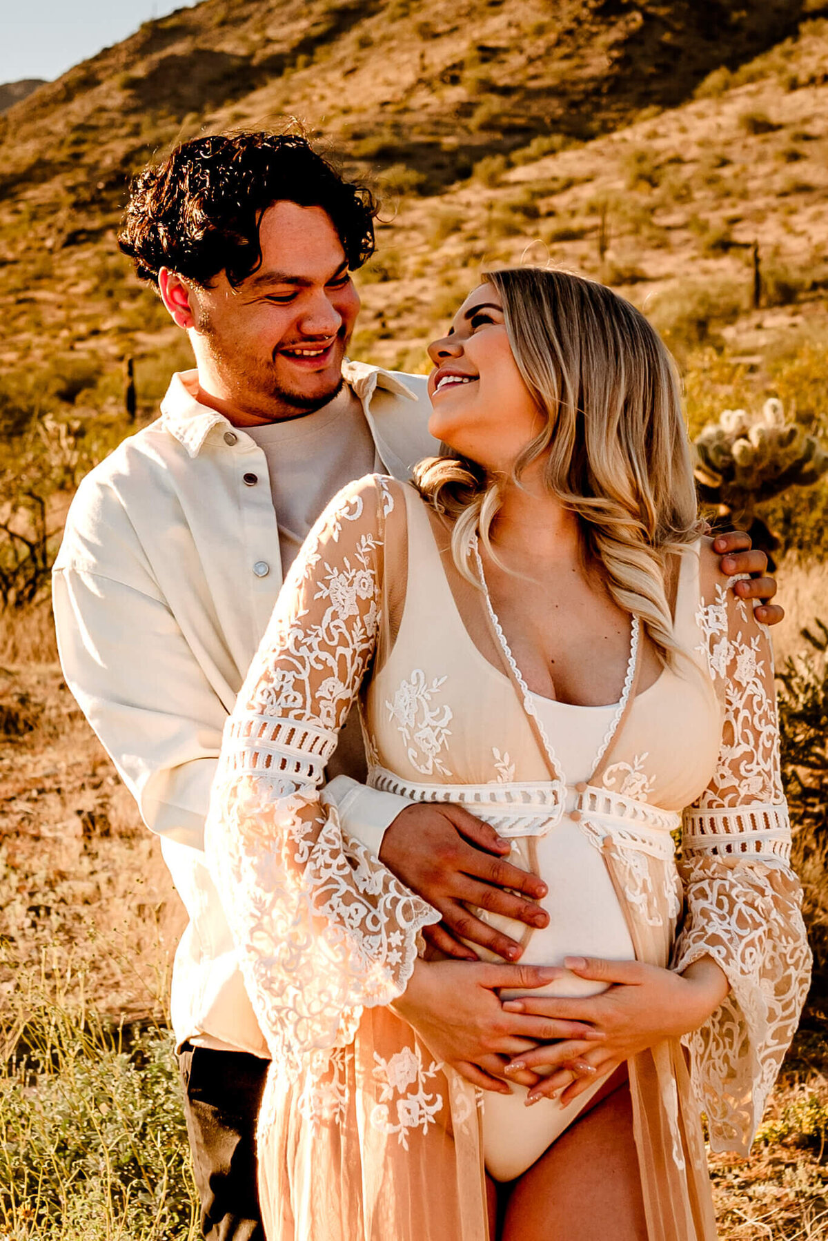 AZ parents smiling while holding maternity baby bump for photographer