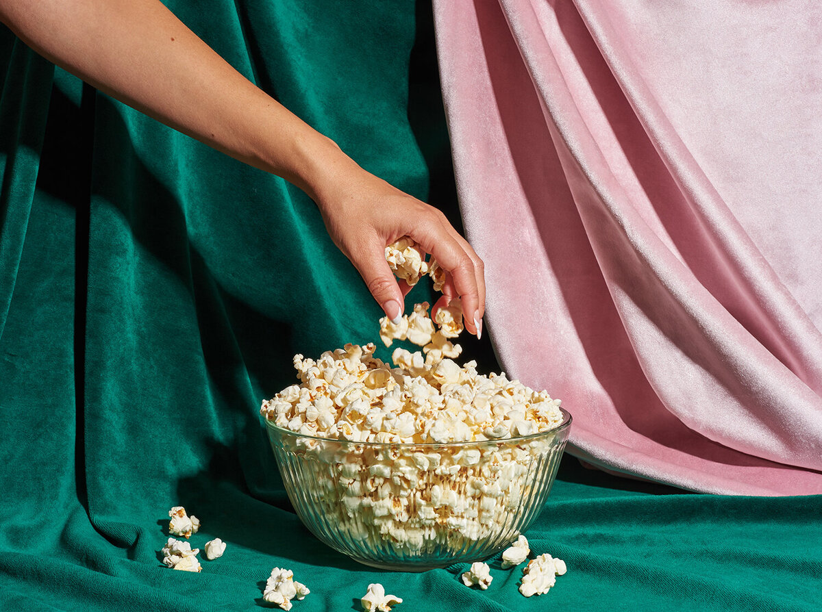 hand reaching into bowl of skinnypop popcorn tabletop photoshoot