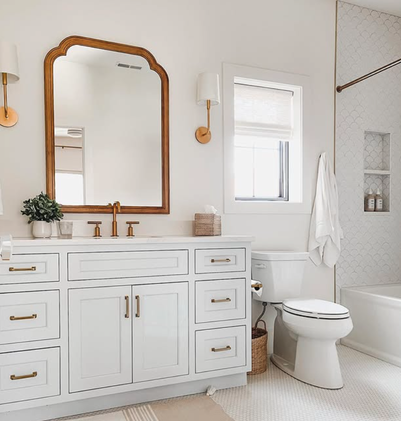 An upstairs guest bathroom includes a custom sky blue vanity with brass hardware and matching sconces