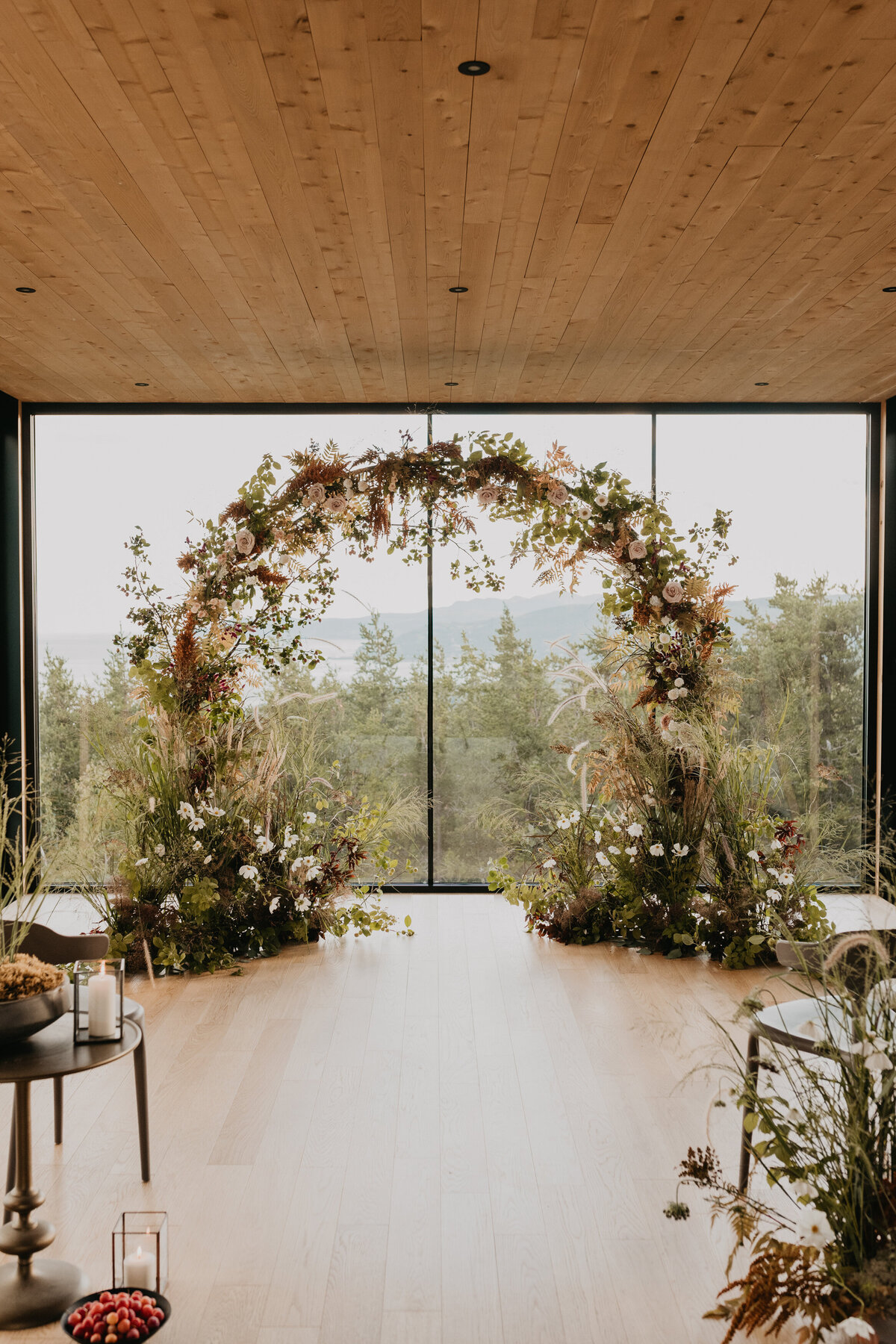 An organic arch of greenery and flowers for a wedding ceremony overlooking the hills of Charlevoix.