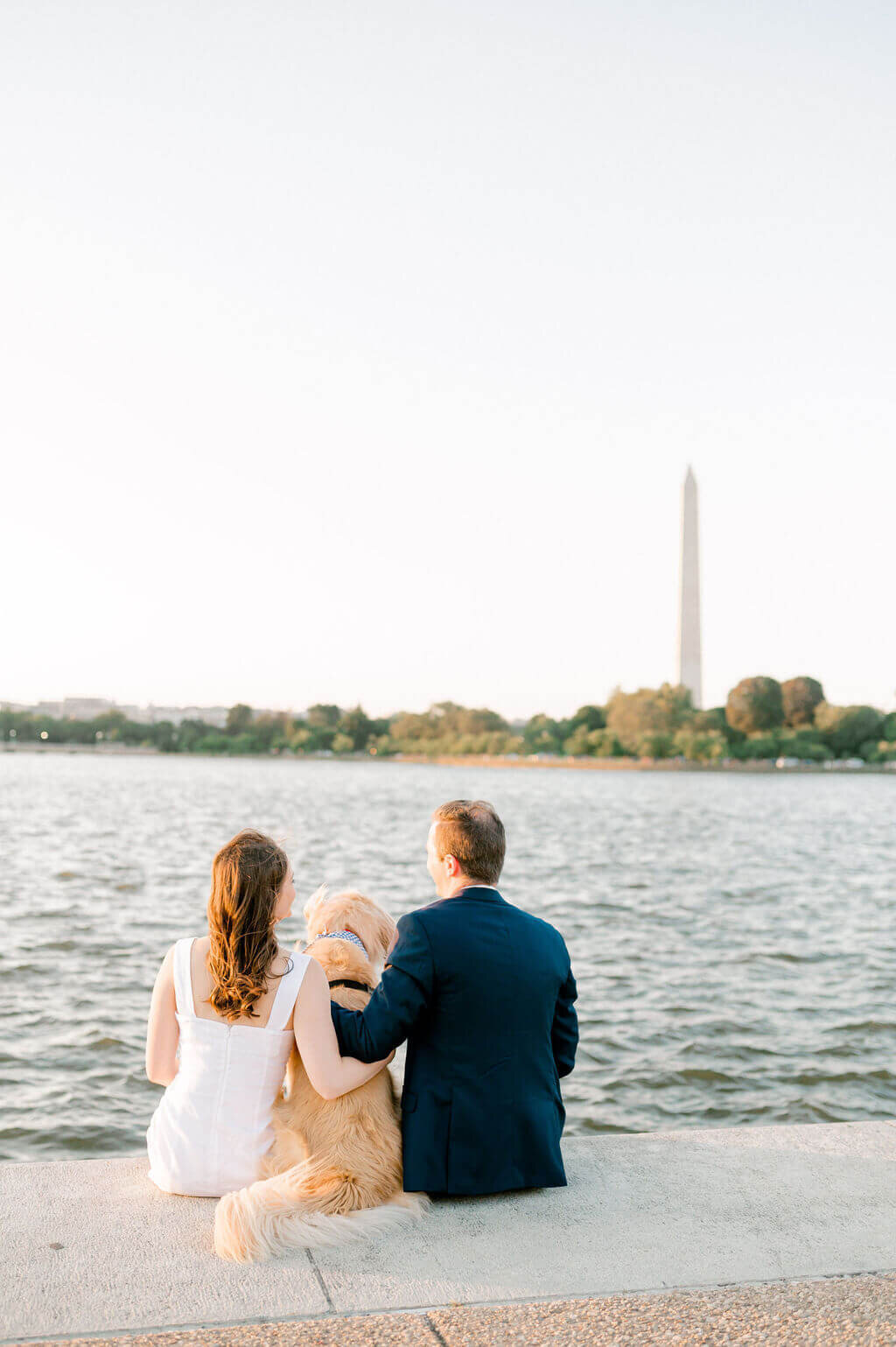 Couple and their dog  sitting in front of Tidal Basin during their engagement photos.