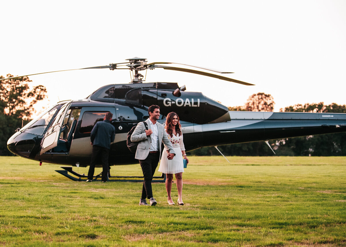 A smartly dressed couple walk away from a helicopter after getting engaged.