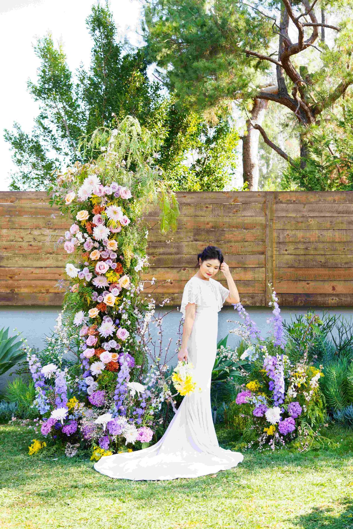Bride  holding a Spring bouquet standing in between colorful floral pillars