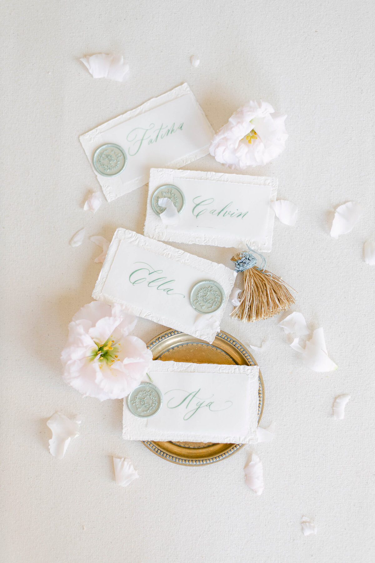 Name cards sit on a soft white background surrounded by flower petals.