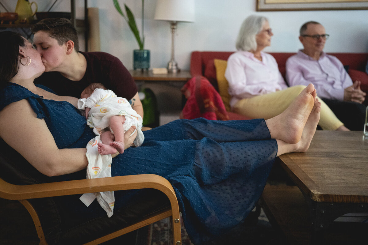 Two mothers with baby and grandparents in the background